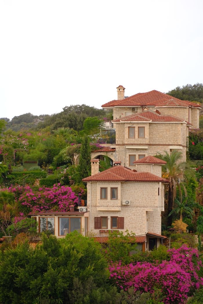 The Art of Drawing Readers In: Your attractive post title goes here Stone villa with red-tiled roofs surrounded by vibrant gardens under an overcast sky.