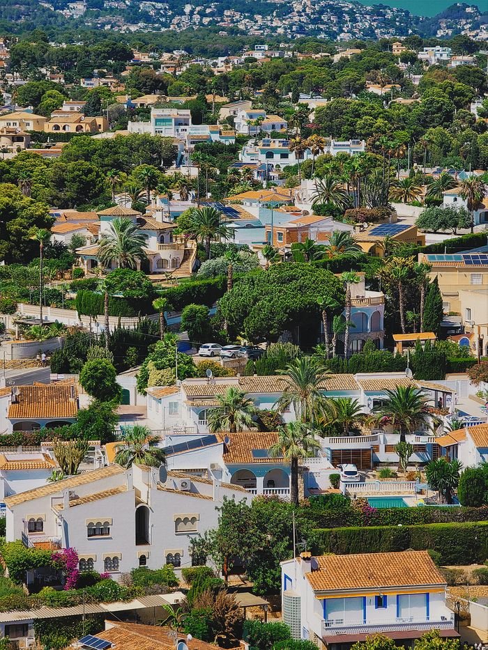 Aerial view of a picturesque Mediterranean village with white villas and lush greenery, capturing summer vibes.